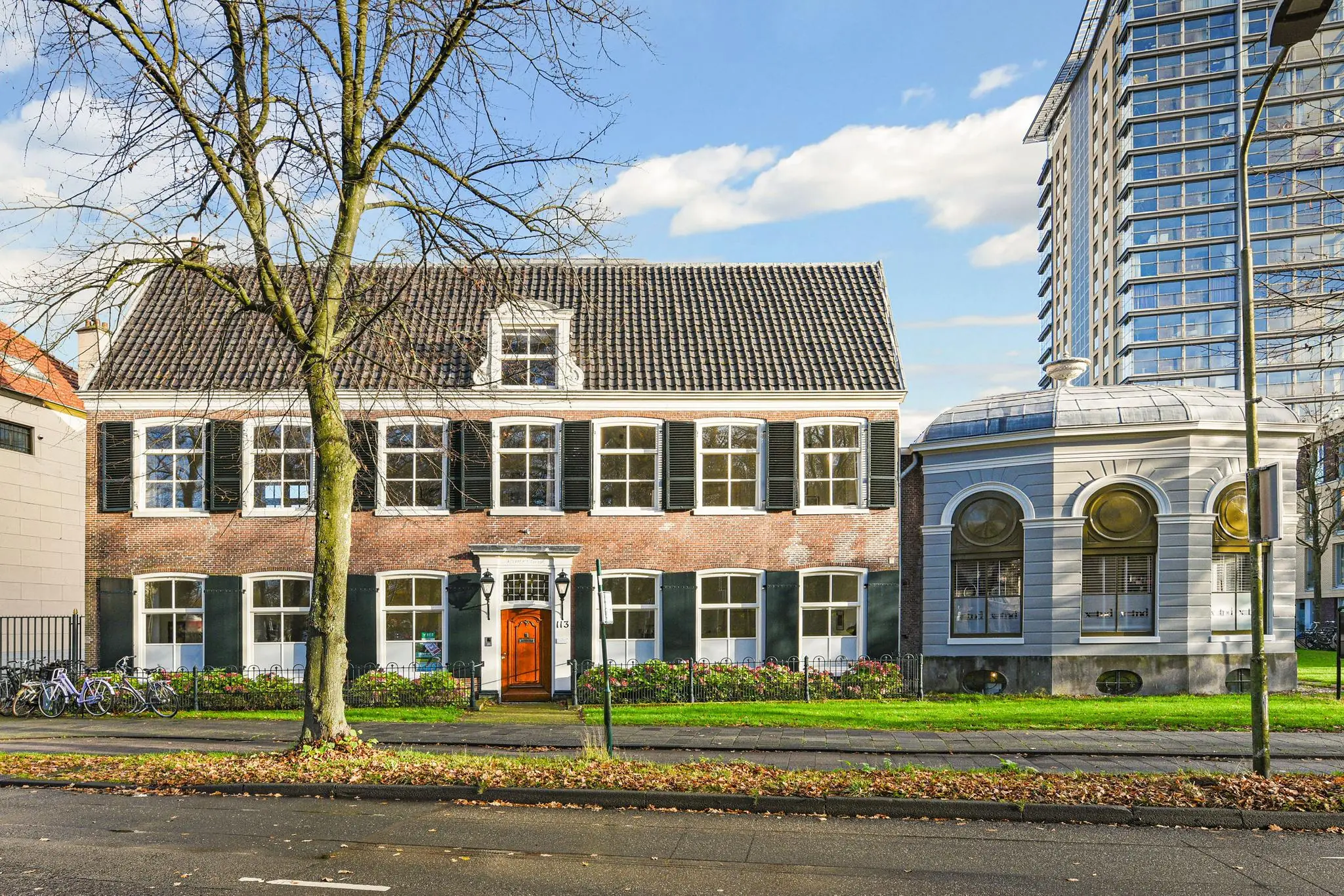 Vooraanzicht van een historisch pand aan de Kleine Houtweg met een klassieke gevel en een moderne flat op de achtergrond.